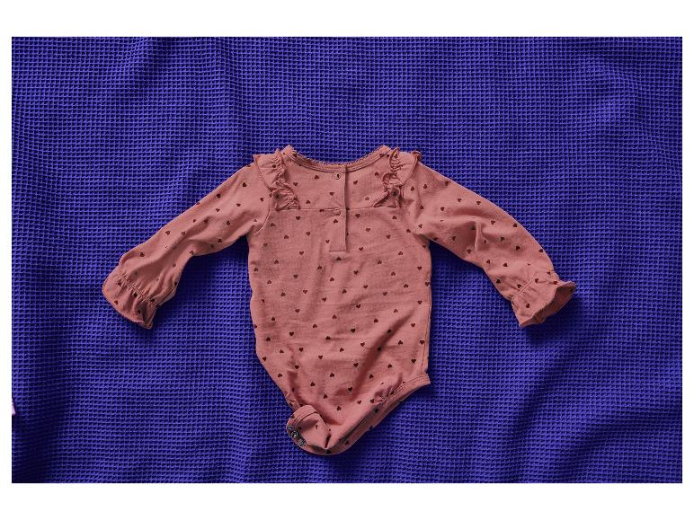 Roze baby romper met hartjes op een blauwe deken