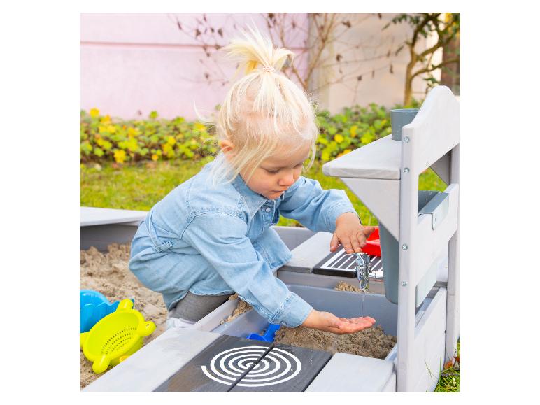 Peuter speelt met een houten modderkeuken en zand.