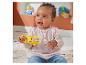 Blauwe baby speelt met een gele apenrammelaar, zittend op een kleed met speelgoed op de achtergrond.
