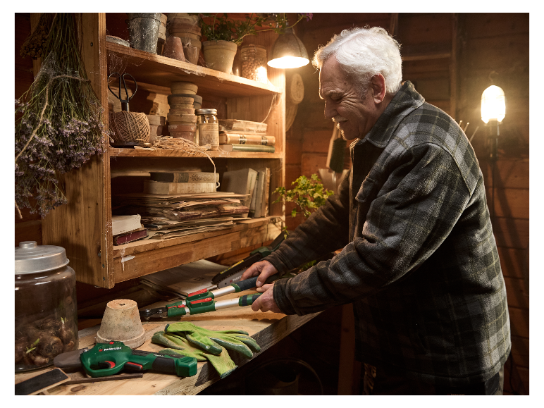 Een oudere man gebruikt Parkside snoeigereedschap in zijn schuur.
