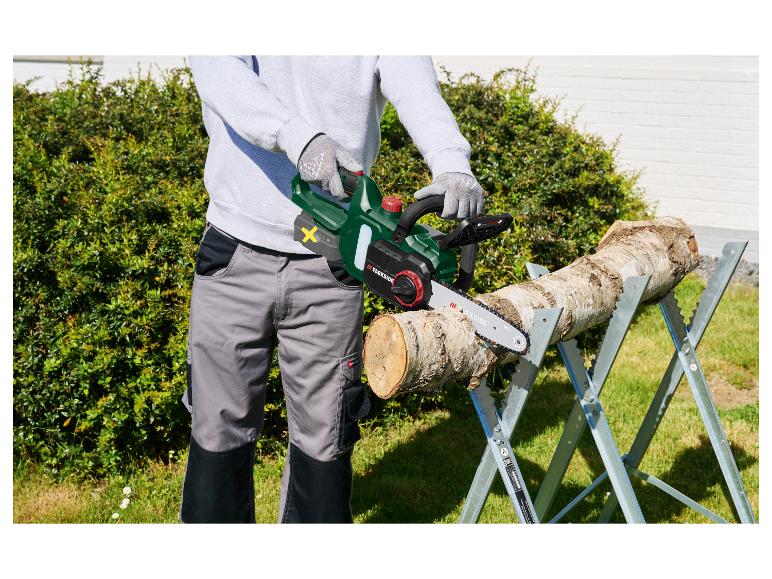 Man met Parkside kettingzaag zaagt hout op een zaagbok.
