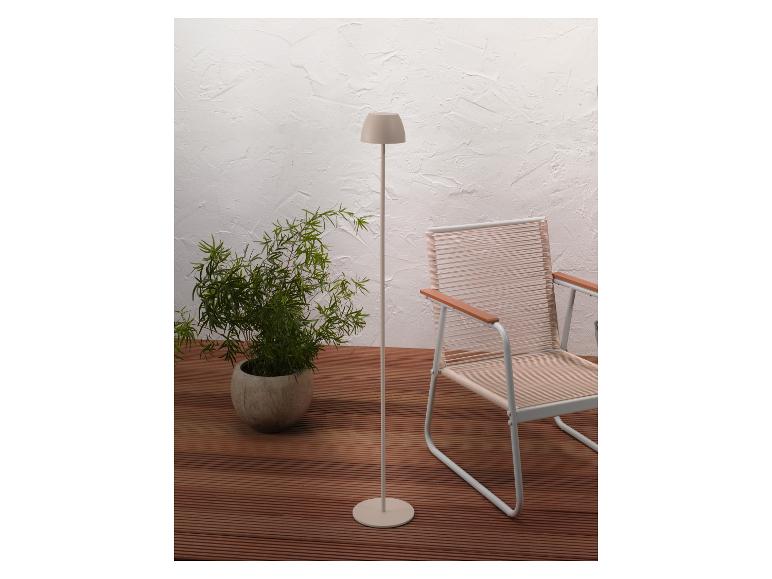 Beige vloerlamp en buitenstoel op een houten terras met een plant.