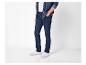 Man draagt donkerblauwe jeans, wit T-shirt en open spijkeroverhemd.
