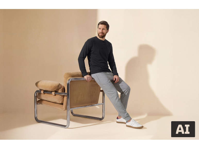 Man in een zwart shirt met lange mouwen en grijze joggingbroek zittend op een fauteuil.