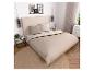 Slaapkamer met een beige bed, dekbed, kussens en een rond vloerkleed, met modern decor.