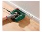 Hand gebruikt een elektrische tacker om een plint aan een houten vloer te bevestigen.