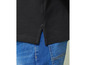 Een zwart poloshirt met zijsplitten, gedragen met blauwe jeans.