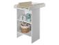 Witte commode met beige aankleedkussen, luiers en speelgoed in een mand.