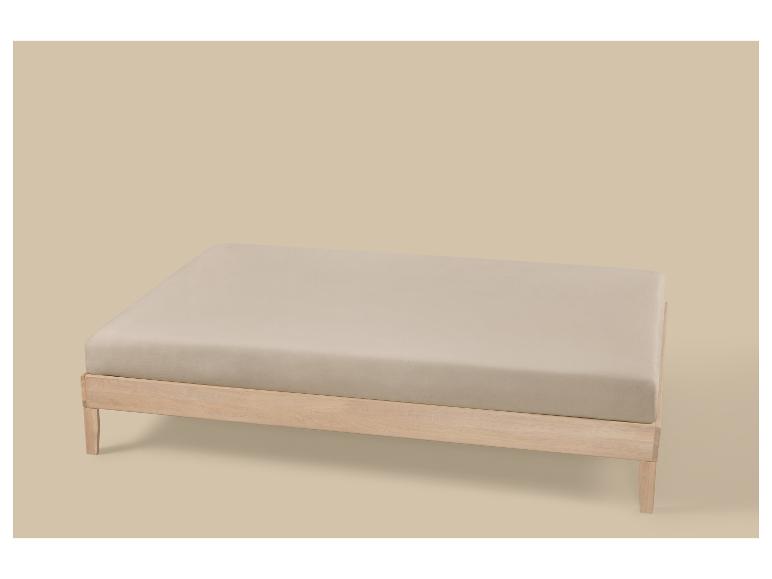 Lichtbeige hoeslaken op een houten bedframe