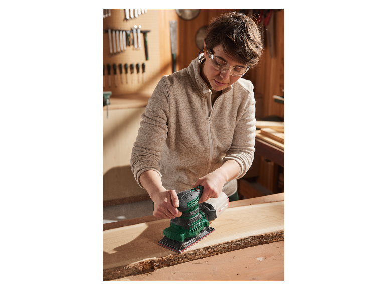 Een vrouw schuurdt hout met een Parkside schuurmachine in haar werkplaats.