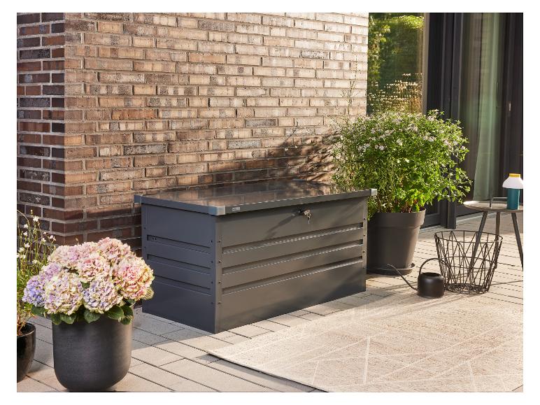 Donkergrijze tuinopbergbox met sleutel, potplanten en een vloerkleed op een terras.