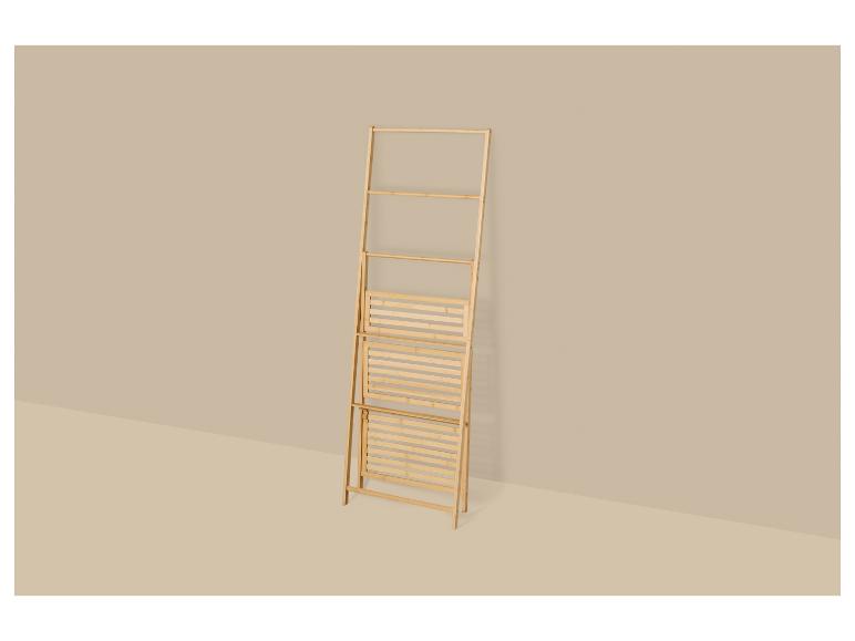 Opvouwbaar bamboe wasrek leunend tegen een beige muur.