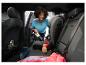 Vrouw stofzuigt auto-interieur met kruimeldief, met kinderzitje en regenlaarzen.