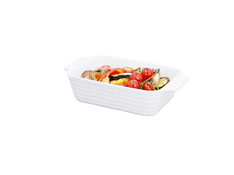 Geroosterde groenten met cherrytomaten, courgette en kruiden in een witte ovenschaal.
