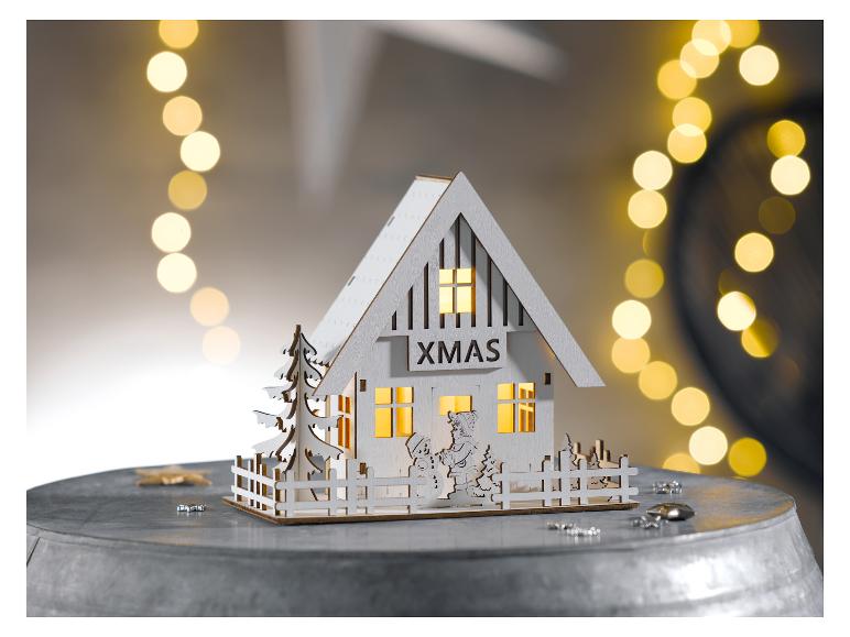 Decoratief houten huisje met lichtjes, 'XMAS'-opschrift en winterse decoraties.