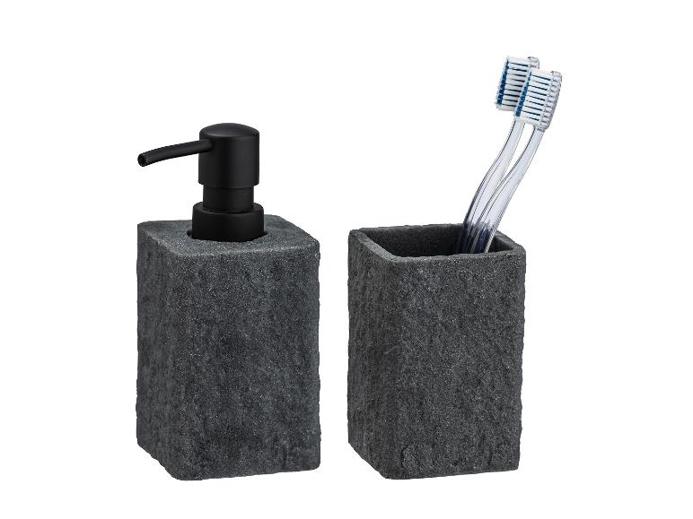 Donkergrijze zeepdispenser en tandenborstelhouder van steen.