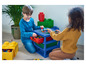 Twee kinderen spelen met Lego-stenen op een blauwe Lego-tafel met lades.