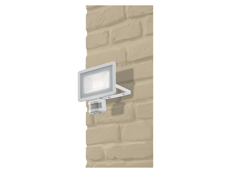 Witte LED-schijnwerper met bewegingssensor op een beige bakstenen muur.