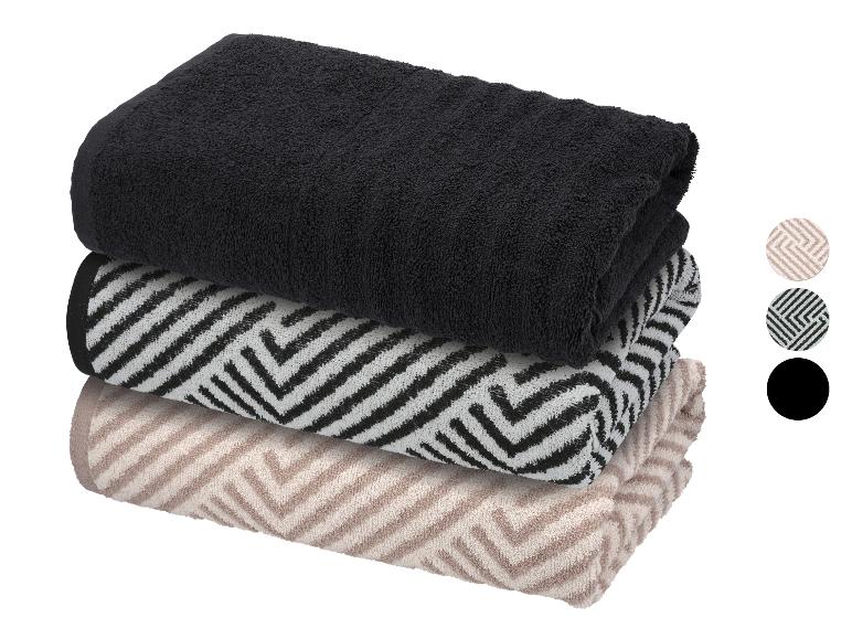 Stapel van drie gevouwen handdoeken: zwart, zwart-wit patroon en beige patroon.