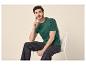 Man in een groen T-shirt en donkere jeans zittend op een witte stoel.