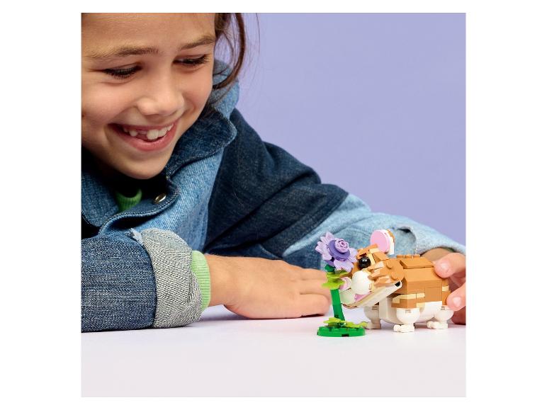 Meisje speelt met een speelgoedhamsterfiguur en een bloem.