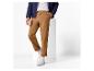 Man in bruine broek en donkerblauwe jas met wit T-shirt en witte sneakers.