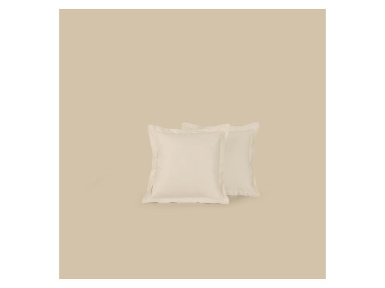 Twee crèmekleurige kussens op een beige achtergrond