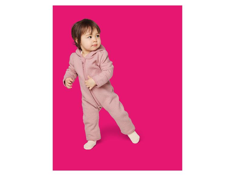 Peuter in een roze hooded fleece jumpsuit, kijkt opzij.