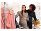 Een zwangere vrouw en haar partner kijken naar kleding die aan een rek hangt.