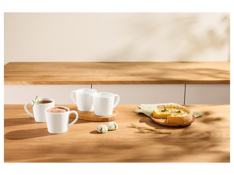 Witte mokken met drankjes, citroentaart en koekjes op een houten tafel.