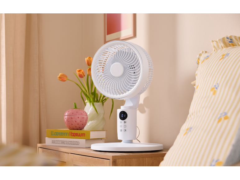 Witte tafelventilator op een houten nachtkastje naast het bed.