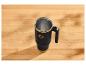 Zwarte thermobeker met gouden accenten op een houten tafel.