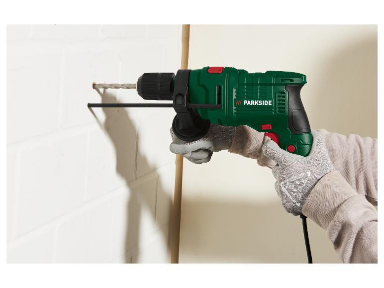 Groene Parkside boormachine in gebruik, boort in een witte muur.