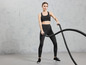 Een vrouw in sportkleding gebruikt een battle rope tijdens een training.