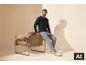 Man in zwart shirt met lange mouwen en grijze joggingbroek, zittend op een fauteuil.