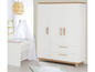 Een witte babywieg met een hemel en een witte kledingkast met houten details.