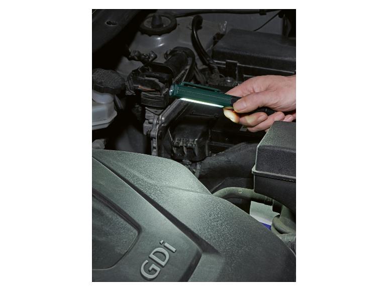 Man verlicht automotor met zaklamp, GDi-opschrift zichtbaar.