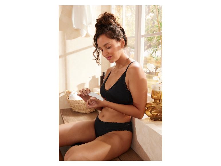 Een vrouw in zwarte lingerie gebruikt een nagelvijl in haar badkamer.