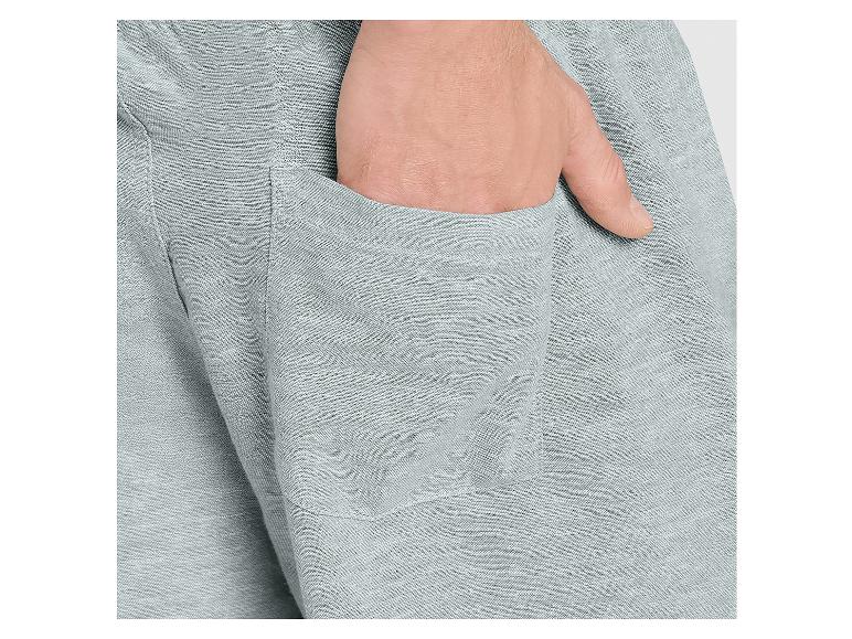 Close-up van een hand in de zak van een grijze broek.