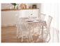 Een witte keukentafel met een bloemetjeskleed en witte stoelen.