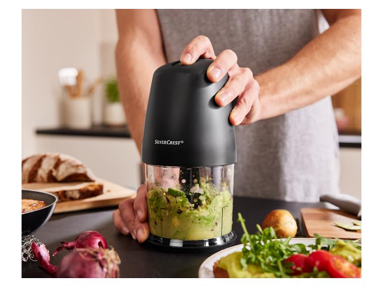 Een hand die een Silvercrest-keukenmachine gebruikt om avocado en rode ui te hakken.