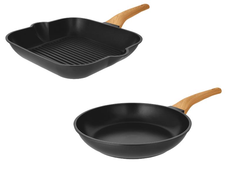 Set zwarte pannen: een vierkante grillpan en een ronde koekenpan met houten handvatten.