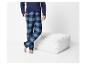 Man in blauw en zwart geruite pyjama naast een witte poef.