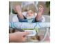 Close-up van een hand die op een knop drukt van een babywipper met een baby op de achtergrond.