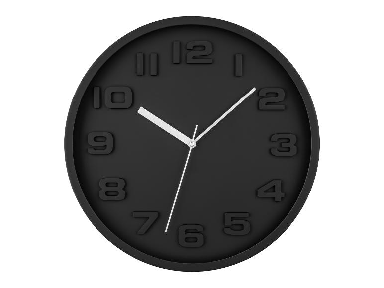 Zwarte, ovale wandklok met witte cijfers.