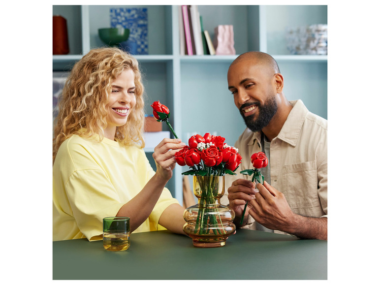 Een stel houdt LEGO-rozen vast in een vaas.