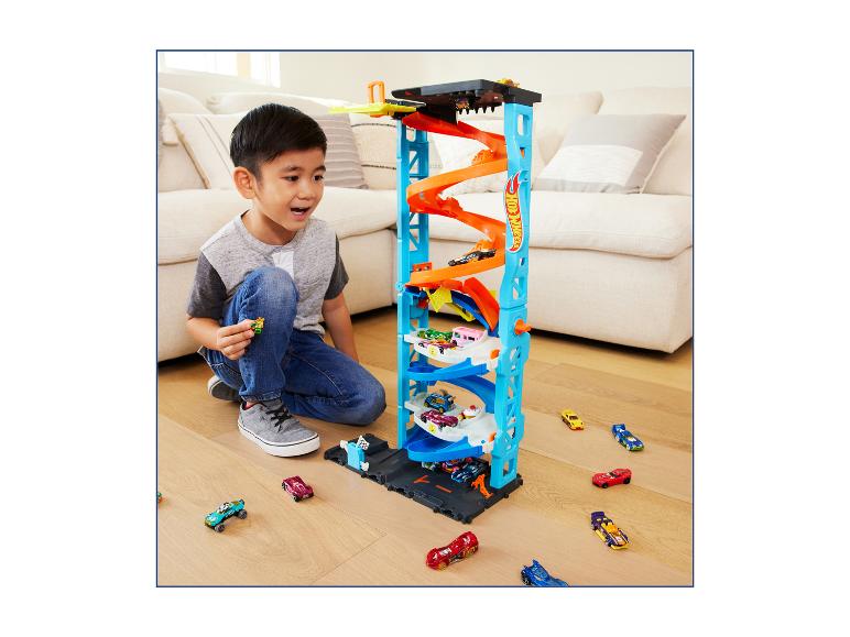 Jongen speelt met een Hot Wheels parkeertoren en speelgoedauto's.