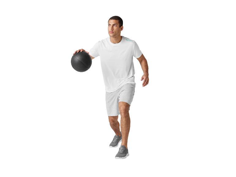 Man in wit t-shirt en grijze shorts dribbelt met een sportbal.