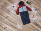 Een rood, blauw en grijs winterpak voor kinderen op een houten vloer met sneeuw.