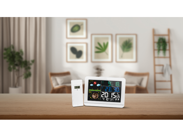 Digitaal weerstation met kleurendisplay en buitensensor op een houten tafel.